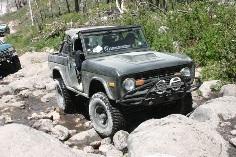 1991 Ford Bronco - Ford Bronco tackles a challenging off-road course with large rocks and water obstacles.