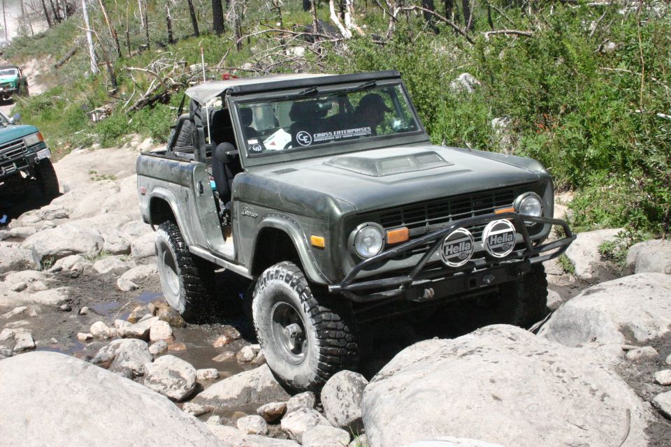 1978 Ford Bronco navigating a rocky trail, with another SUV visible on the left