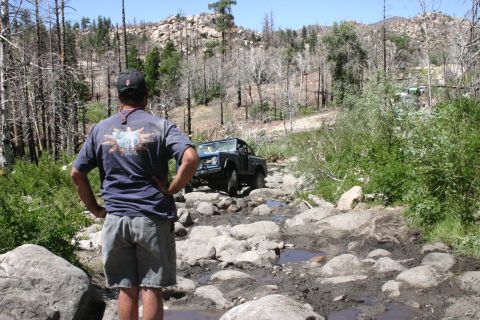 1991 Ford Bronco - A blue 1991 Ford Bronco navigates a challenging rocky and muddy off-road trail.