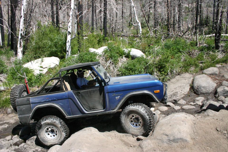 Blue first-generation Ford Bronco off-roading over rocks