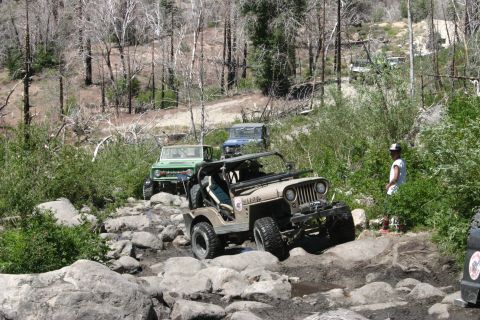 1991 Ford Bronco - Multiple Jeeps tackle a difficult rocky path during an off-road excursion.