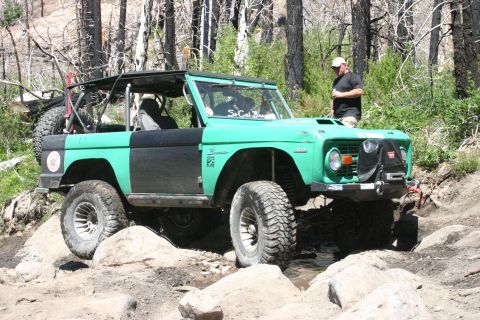 1991 Ford Bronco - This classic Ford Bronco is navigating a rocky off-road trail with a person watching.
