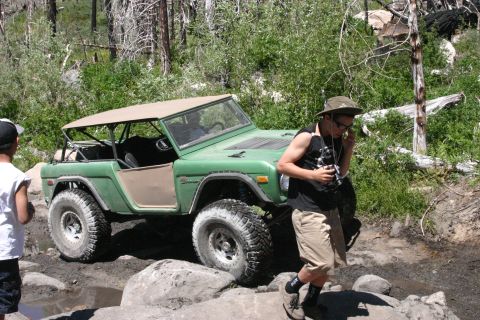 1991 Ford Bronco - A first-generation Ford Bronco navigates a rocky trail, its doors removed for an open-air experience.