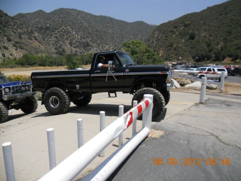 1986 Ford Bronco - A lifted black 1979 Ford F-150 pickup truck is parked next to another off-road vehicle.