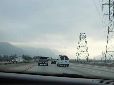2003 Ford Crown Victoria - Driving POV on a multi-lane highway toward hills, lattice transmission towers at right.