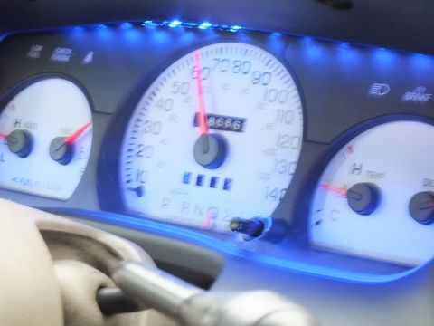 2003 Ford Crown Victoria - Close-up of a white-faced gauge cluster with blue backlight showing PRND gear positions.