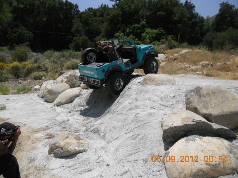 1986 Ford Bronco - An off-road vehicle navigates a challenging rocky terrain on a sunny day.