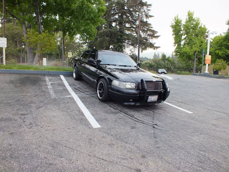 Black Ford Crown Victoria front quarter view, lowered on black wheels with push bar