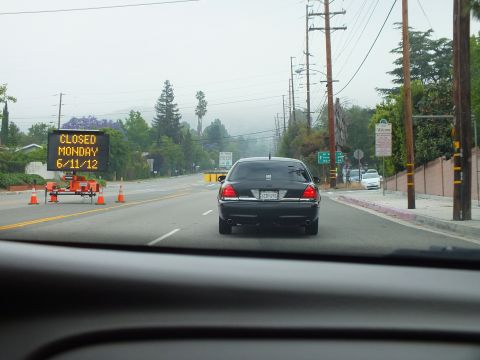 2003 Ford Crown Victoria - Following a black full-size sedan on a road past an orange electronic sign reading CLOSED MONDAY 6/11/12.