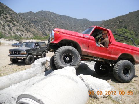 1986 Ford Bronco - Two Broncos navigate a challenging rocky obstacle course in a dry, mountainous area.