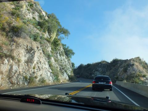 2003 Ford Crown Victoria - Following a black full-size sedan up a mountain road flanked by jagged rock outcrops.