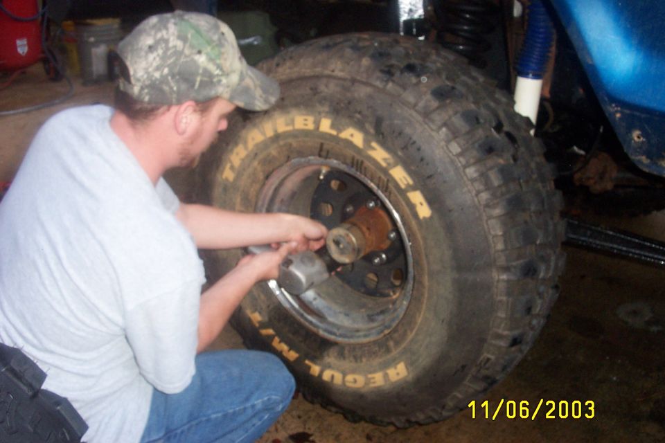 Impact gun removing lug nuts from a Trailblazer M/T tire on a lifted blue truck