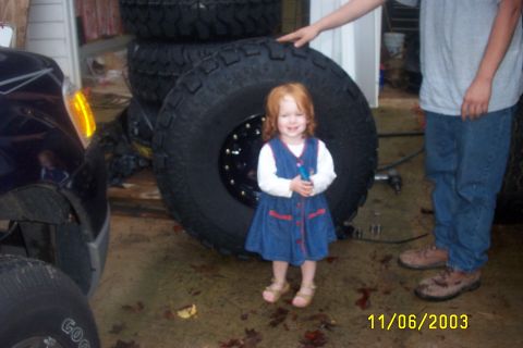 1979 Ford F-150 - A young child poses next to oversized tires in a garage setting.