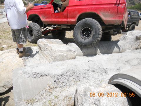 1986 Ford Bronco - Off-road SUV with large tires is driven over a rocky obstacle course.