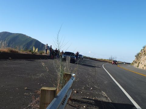 2003 Ford Crown Victoria - Roadside overlook above a hazy valley; people stand by parked cars as a vehicle approaches around the bend.