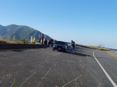 2003 Ford Crown Victoria - man walks toward a parked SUV on a wide paved overlook; others gather at the ridge under clear skies.