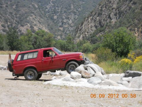 1986 Ford Bronco - This red 1986 Ford Bronco is shown off-roading through a rocky canyon.