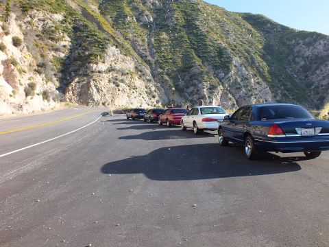 2003 Ford Crown Victoria - Sedans parked diagonally along a mountain road, blue Crown Victoria in front with California plate