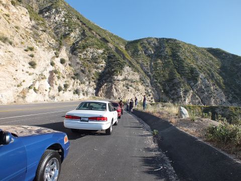 2003 Ford Crown Victoria - White sedan with California plate parked behind a blue car, people standing at the canyon edge