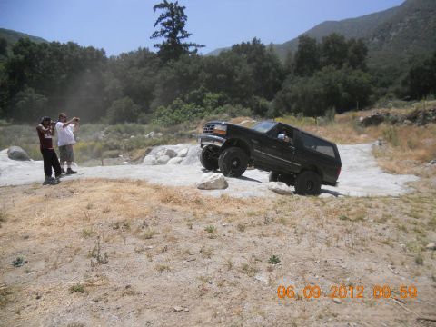 1986 Ford Bronco - A black 1992 Ford Bronco navigates a rocky trail with two people watching.