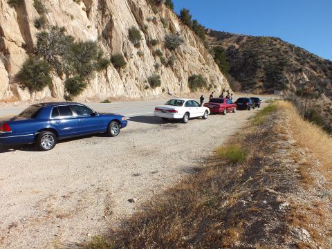2003 Ford Crown Victoria - Blue full-size sedan parked at front of a line of cars along a mountain highway pullout