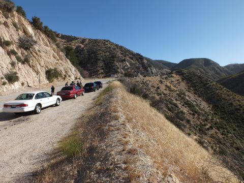 2003 Ford Crown Victoria - White and maroon sedans on a mountain road turnout, ridge dropping away to the right