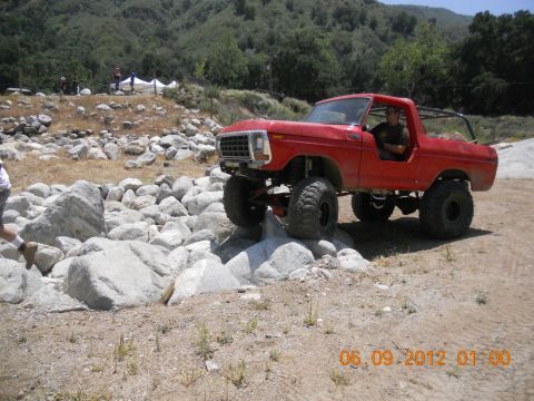 1986 Ford Bronco - A red off-road SUV is shown traversing a challenging rocky landscape.