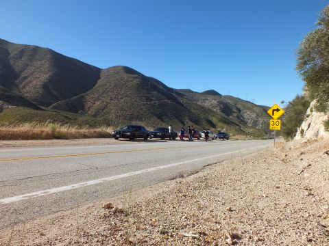 2003 Ford Crown Victoria - Mountain highway stretching toward a curve sign, small group of cars parked far down the shoulder