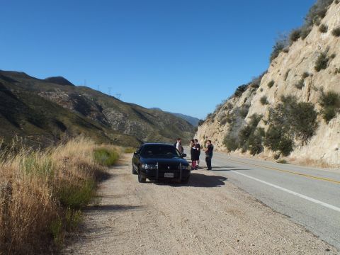 2003 Ford Crown Victoria - Front view of a dark sedan parked at a mountain turnout with a few people standing beside it