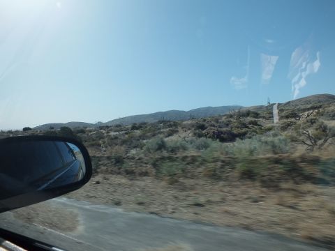 2003 Ford Crown Victoria - Roadside desert hills and scrub viewed from a moving car, side mirror in frame under clear blue sky
