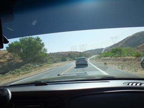 2003 Ford Crown Victoria - View through a windshield following a silver sedan on a curving desert road lined with transmission towers