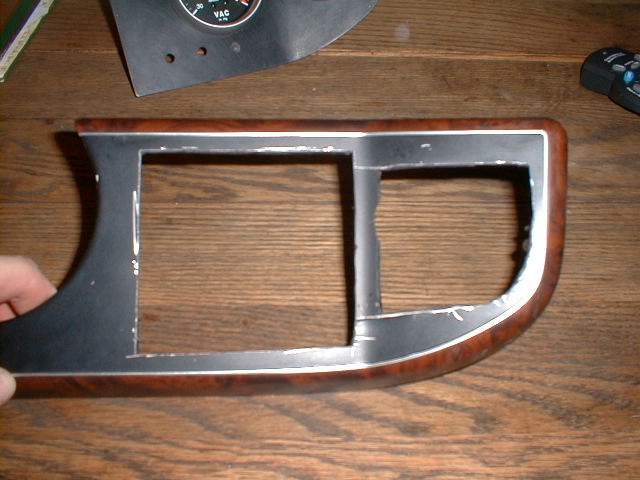 Removed dash bezel with wood-grain trim and two openings on a wood table