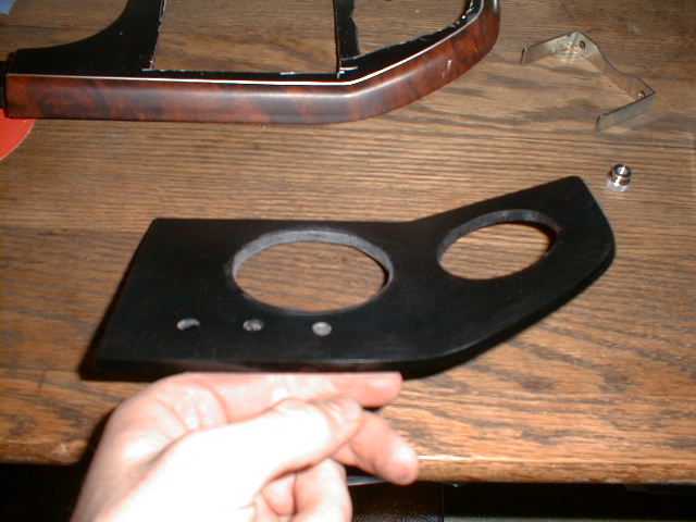Custom-cut flat black gauge panel with round and oval openings on a workbench