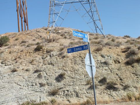 2003 Ford Crown Victoria - Cheseboro Rd and Mt. Emma Rd signs mounted on a pole against an eroded desert hillside.
