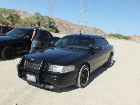 2003 Ford Crown Victoria - Blacked-out Crown Victoria with grille guard and dark alloy wheels at a desert meetup