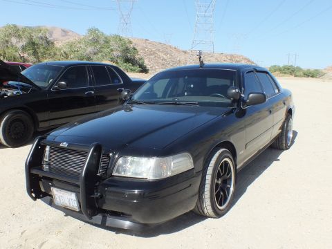 2003 Ford Crown Victoria - Front three-quarter of a blacked-out Crown Victoria with grille guard on dirt ground