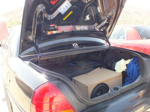 2003 Ford Crown Victoria - Sedan trunk holding a subwoofer enclosure with car-audio stickers on the underside of the lid