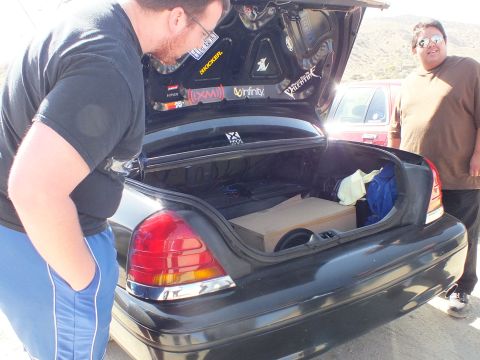 2003 Ford Crown Victoria - Two men around an open sedan trunk fitted with a subwoofer and audio-brand decals