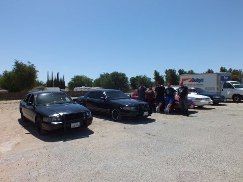 2003 Ford Crown Victoria - Sedans lined up on a gravel lot next to a Budget moving truck and white van