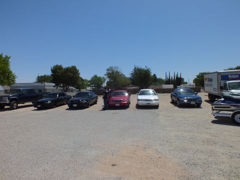 2003 Ford Crown Victoria - Five full-size sedans parked across a gravel lot beside a pickup and Budget rental truck.