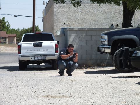 2003 Ford Crown Victoria - photographer crouches to shoot beside a silver Nissan Frontier and a dark pickup.