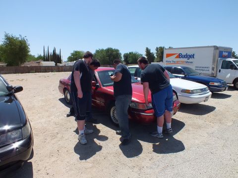 2003 Ford Crown Victoria - Group leans over the open front of a maroon Grand Marquis at a sedan meet.