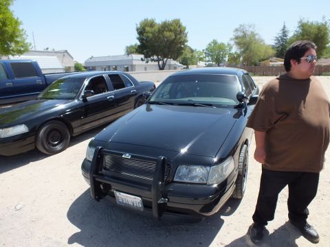 2003 Ford Crown Victoria - Black Crown Victoria fitted with a chrome push bar as a man stands at the fender.