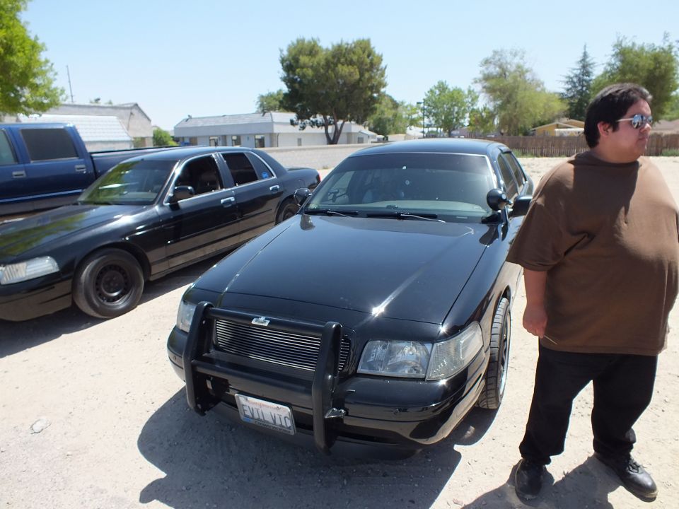 Black Crown Victoria with chrome brush guard and man in sunglasses beside it