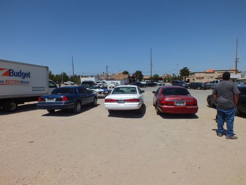2003 Ford Crown Victoria - Blue, white and red full-size sedans lined up rear-first near a Budget moving truck