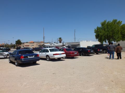 2003 Ford Crown Victoria - Blue, silver, maroon and black sedans plus pickups parked across an open dirt lot