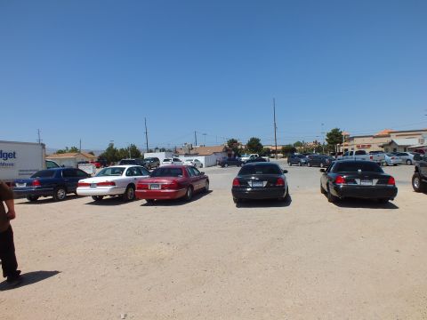 2003 Ford Crown Victoria - Blue, silver, red and black sedans plus a dark BMW lined up rear-first on dirt