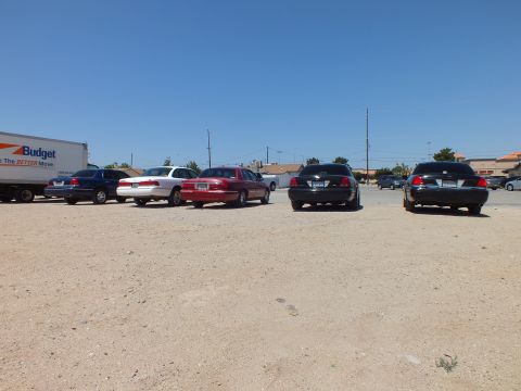 2003 Ford Crown Victoria - Blue, white, red and black sedans lined up rear-first near a Budget moving truck