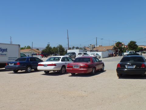 2003 Ford Crown Victoria - Blue, white, red and black sedans staged on a sandy lot under a wide blue sky