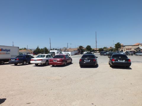 2003 Ford Crown Victoria - spread of full-size sedans on gravel, Budget box truck at left and a strip mall in the distance